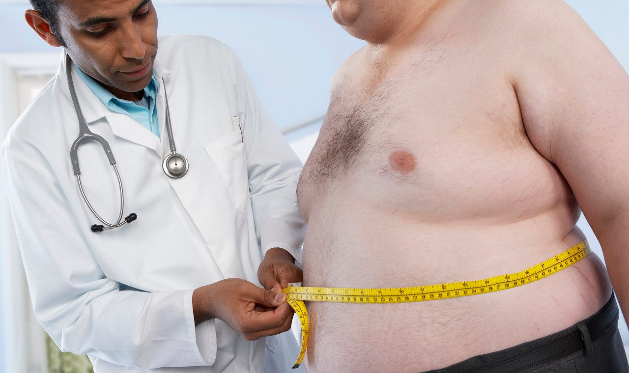 Medical consultation. General practioner measuring the waist of an obese patient. --- Image by © Adam Gault/Science Photo Library/Corbis