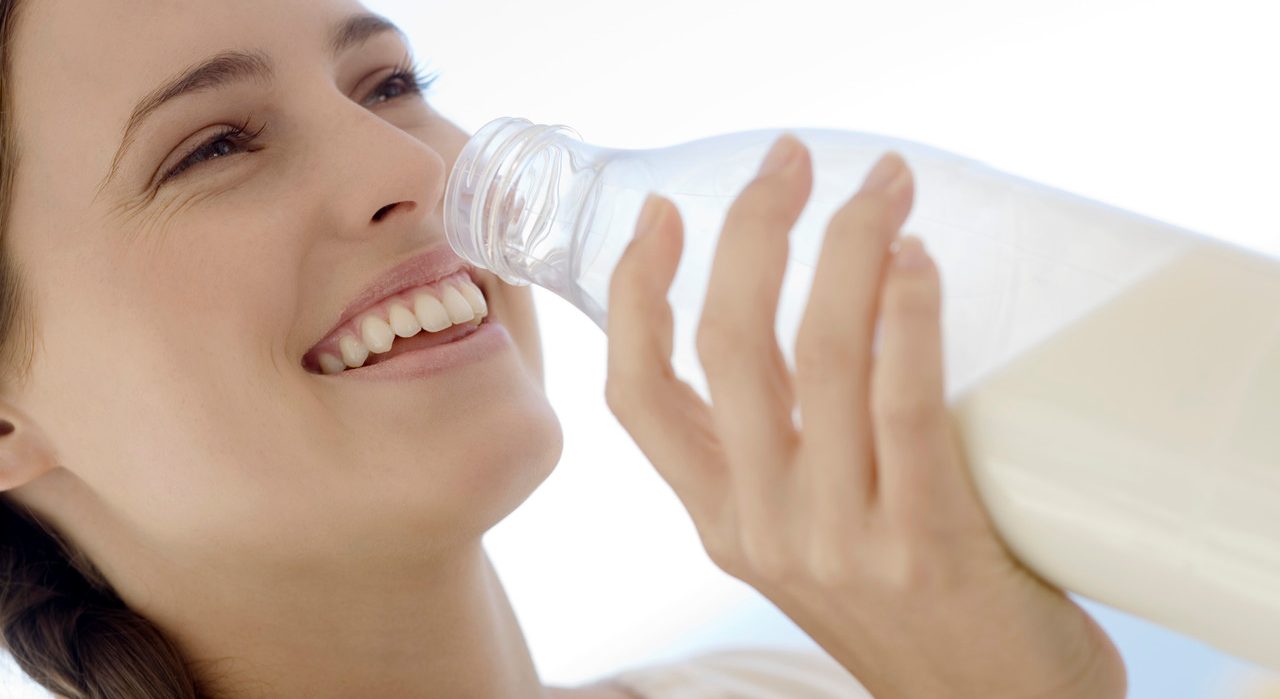 Portrait of a young woman drinking milk from the bottle, outdoors --- Image by © Elie Bernager/Onoky/Corbis