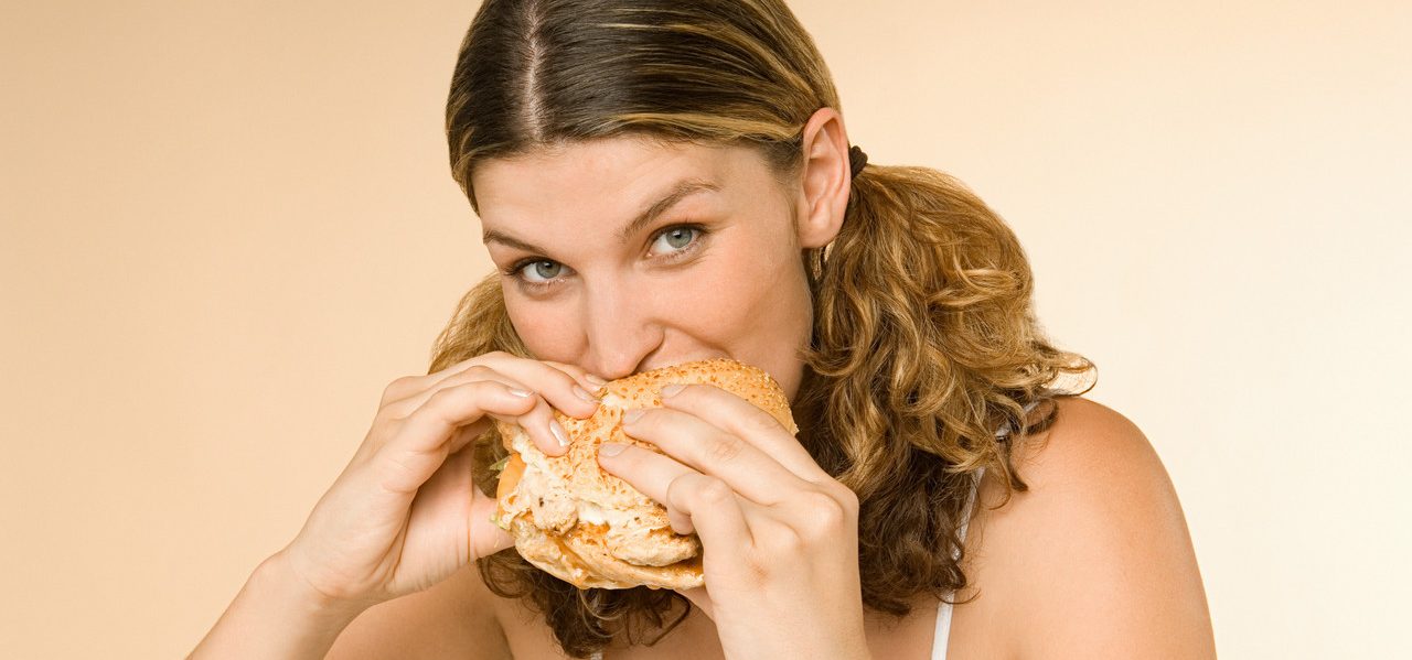 Woman eating a burger --- Image by © Image Source/Corbis