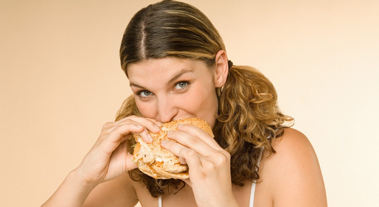 Woman eating a burger --- Image by © Image Source/Corbis