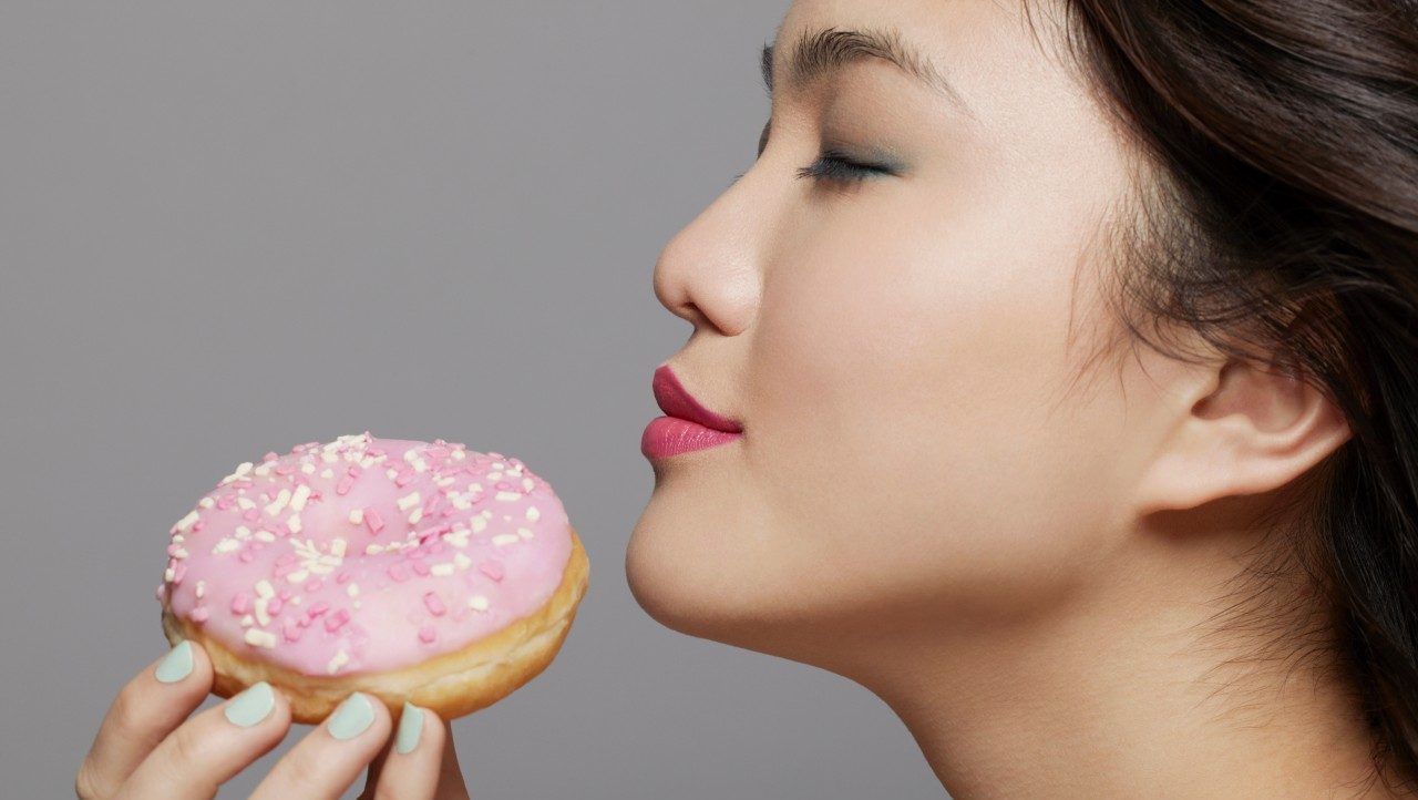 Young woman holding doughnut --- Image by © Emma Kim/Corbis