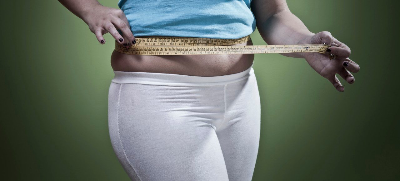 Woman measuring her waistline --- Image by © Walter Zerla/cultura/Corbis