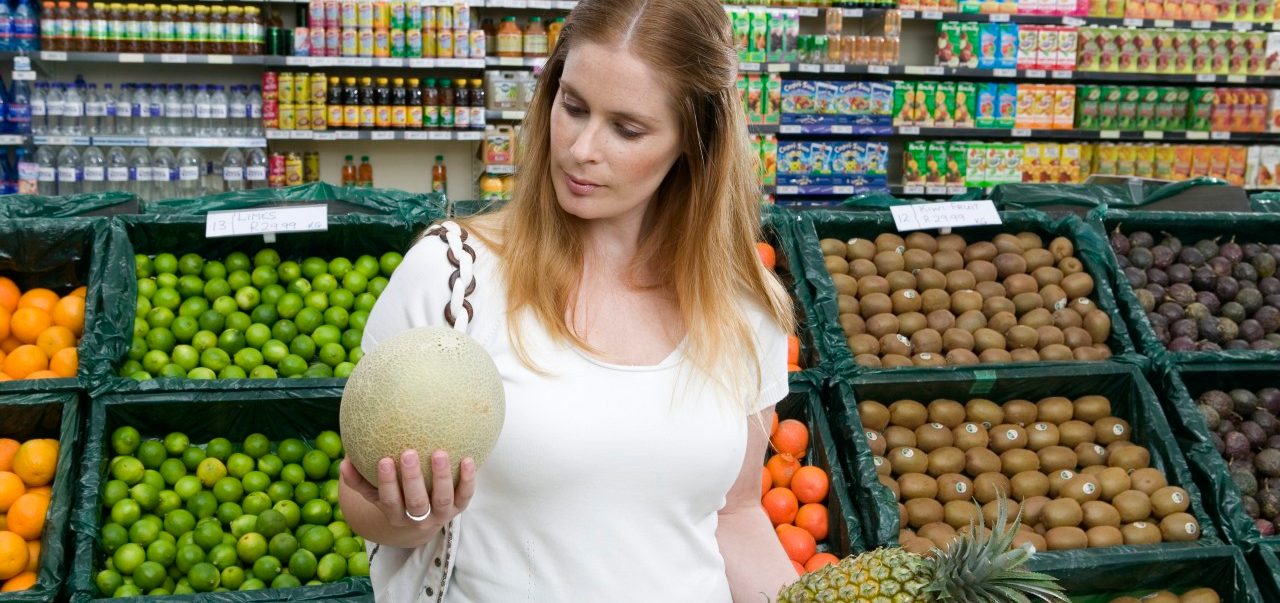 0042-11-30T00:00:00.000Z Woman holding melon and pineapple in supermarket --- Image by © 2/B2M Productions/Ocean/Corbis