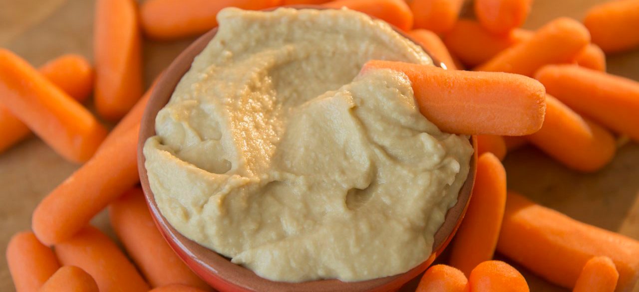 42-64649004 25 Jul 2014 --- Studio shot of hummus and baby carrots --- Image by © Jamie Grill/Tetra Images/Corbis