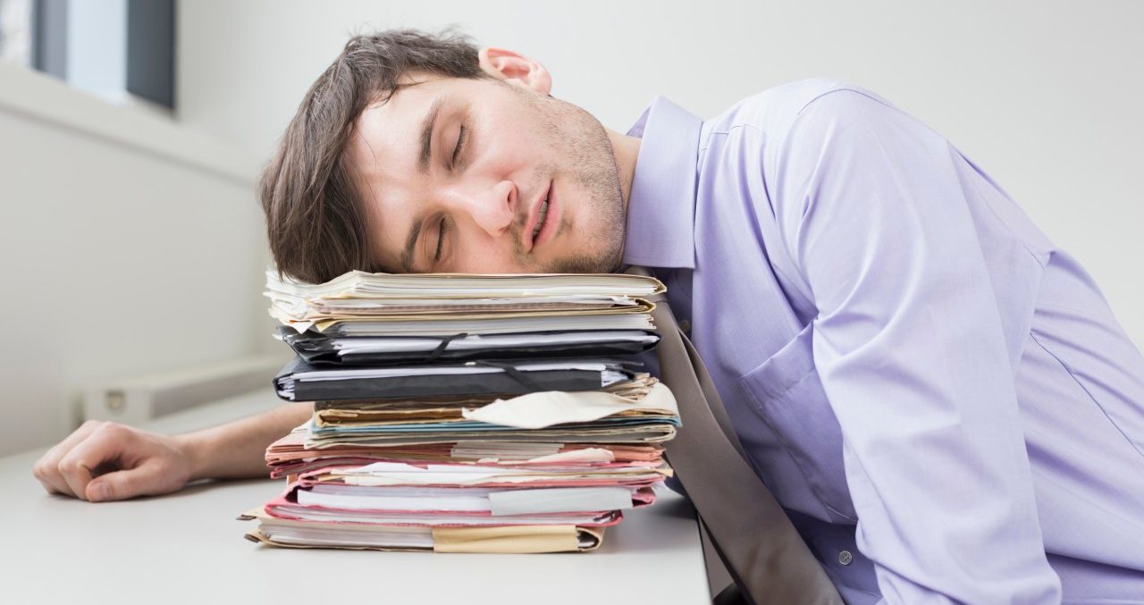 12 Feb 2013 --- Businessman sleeping on stack of files in office --- Image by © Dreet Production/Corbis