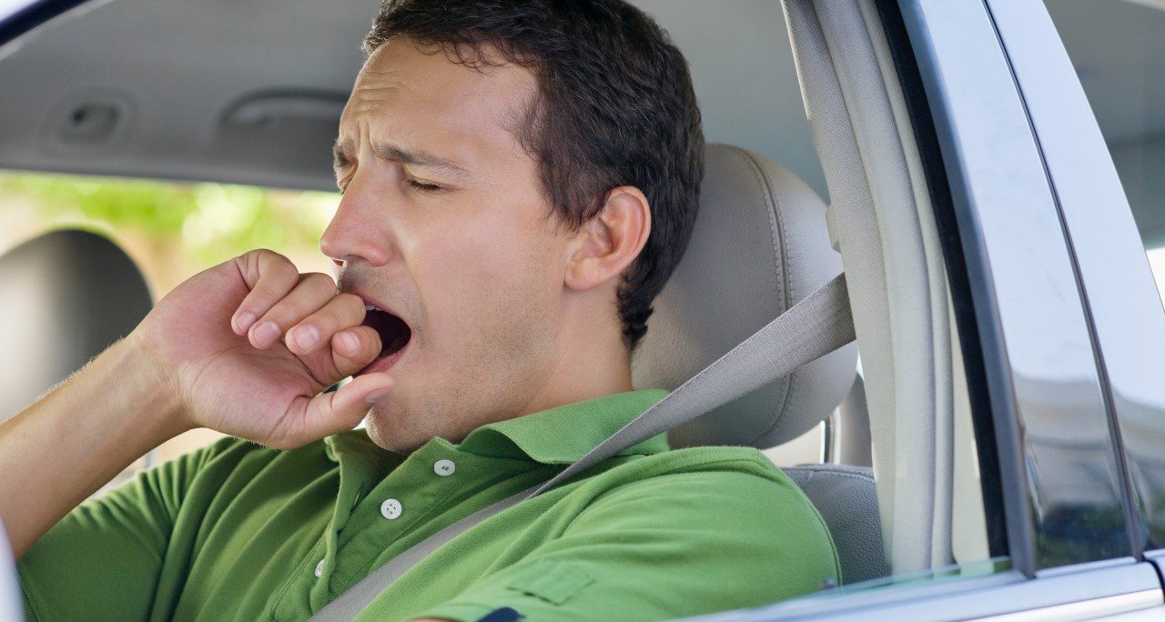Mid adult man yawning while driving a car --- Image by © Eric Audras/Onoky/Corbis