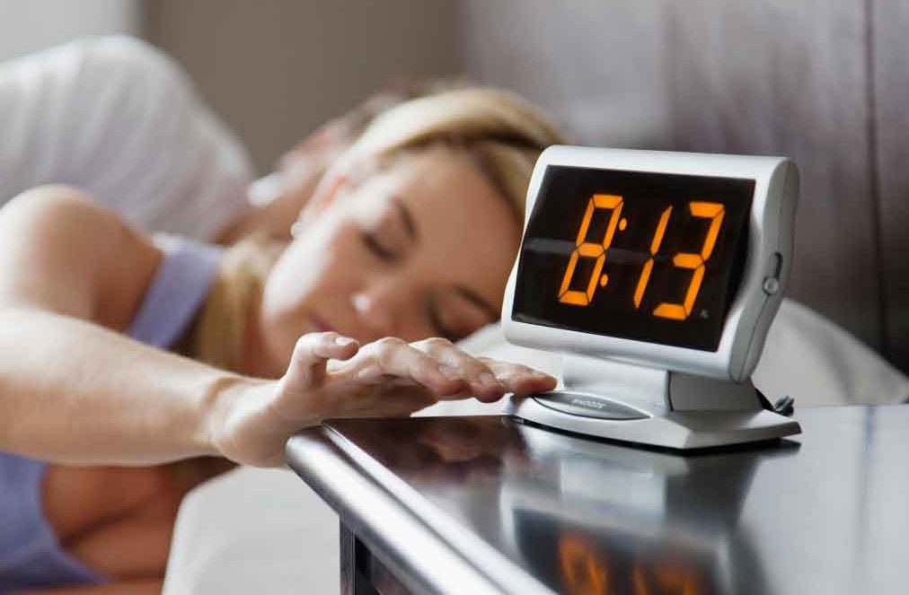 Woman reaching for alarm clock Woman reaching for alarm clock