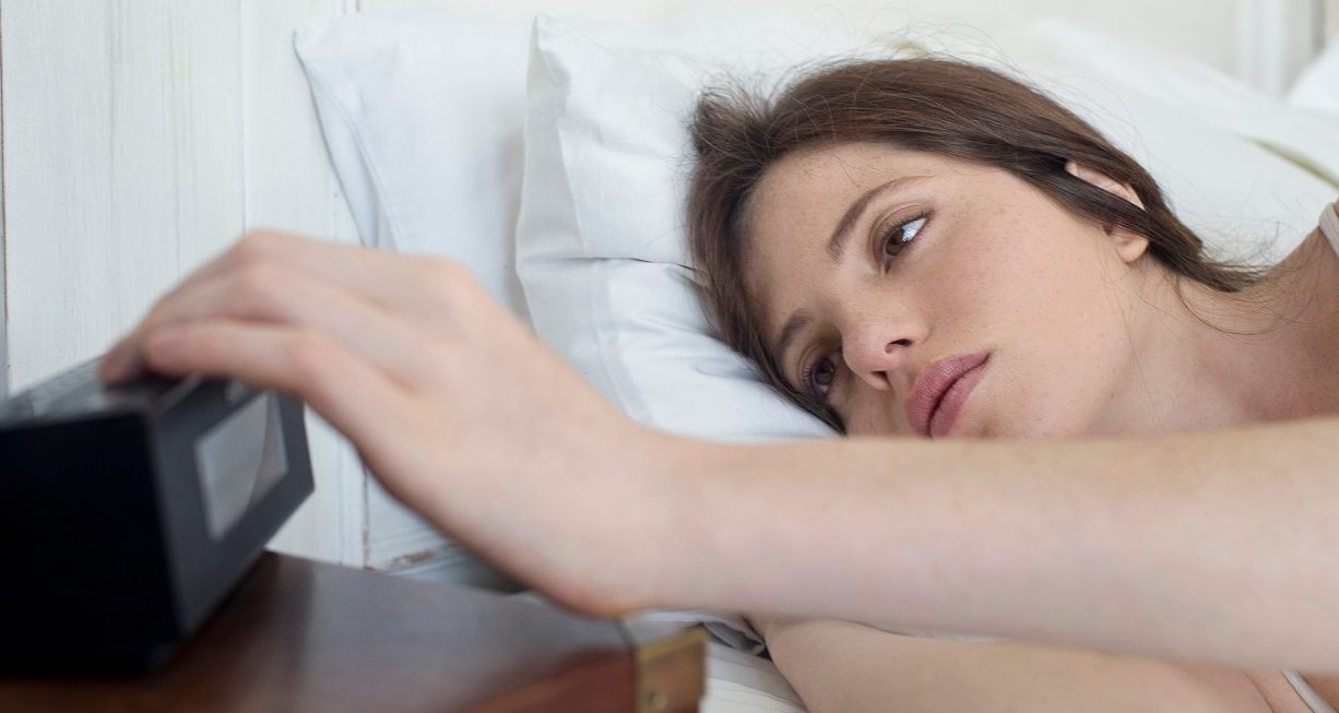 18 Feb 2014 --- Woman in bed pressing alarm clock snooze button --- Image by © Frederic Cirou/PhotoAlto/Corbis